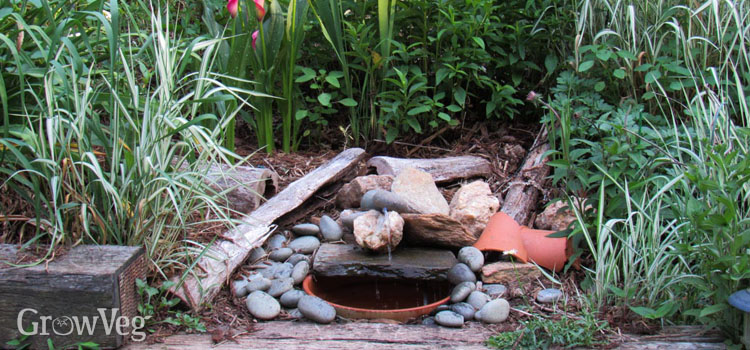 Solar fountain water feature in a garden bed